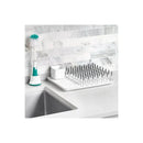 OXO Tot Bottle Drying Rack in gray with angled pegs for bottle drying, accompanied by a bottle brush and small container.