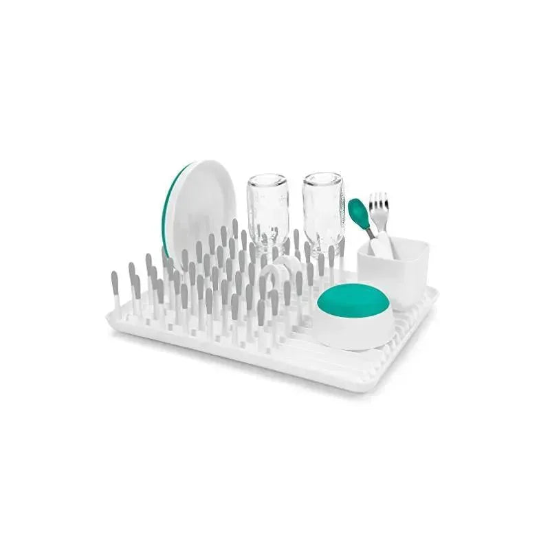 Gray OXO Tot Bottle Drying Rack featuring various bottle parts, glasses, and utensils placed on a drying surface.