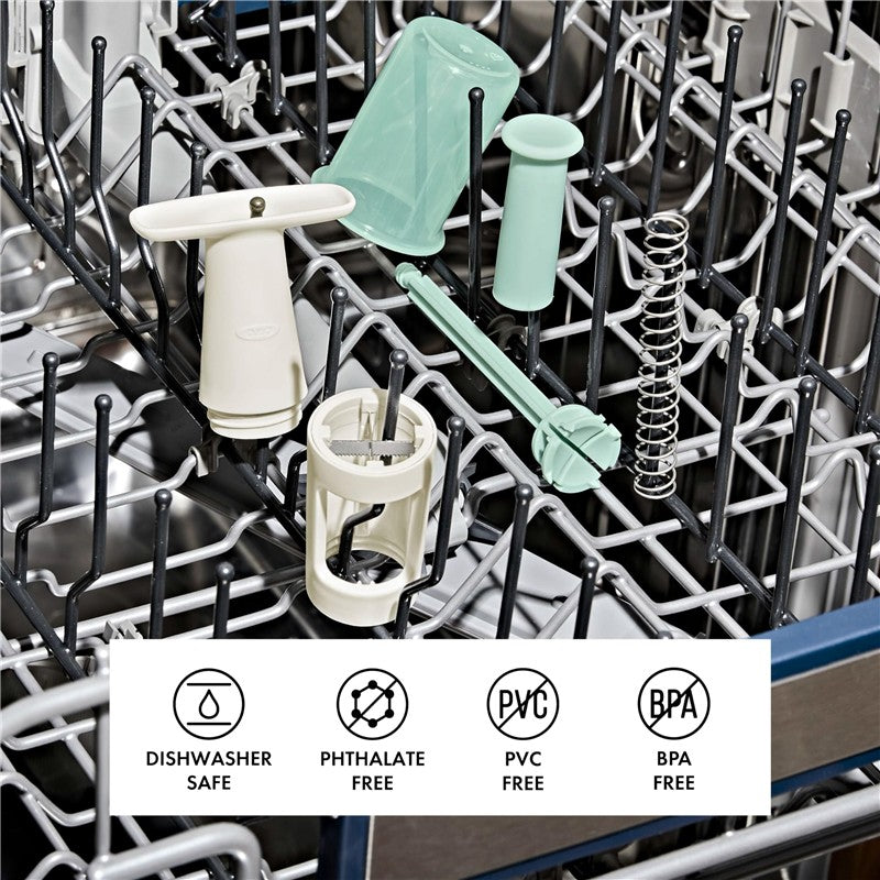 OXO Tot Grape Cutter components displayed in a dishwasher, featuring various safe material icons: dishwasher safe, BPA free, PVC free.