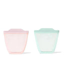 Two silicone reusable bags in opal green and blossom pink, designed for food storage, standing upright.