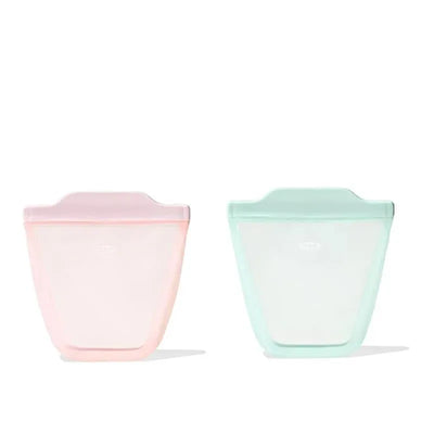 Two silicone reusable bags in opal green and blossom pink, designed for food storage, standing upright.