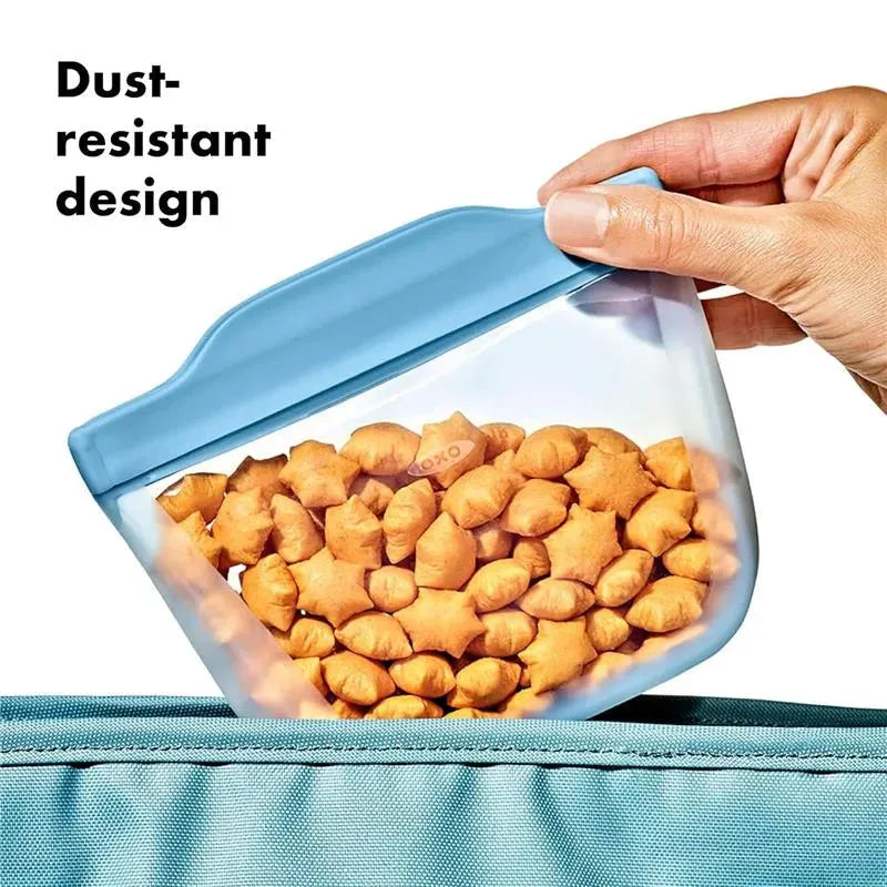 Oxo Tot silicone reusable bag in blue, filled with star-shaped snacks, highlighting its dust-resistant design.