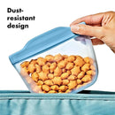 Oxo Tot silicone reusable bag in blue, filled with star-shaped snacks, highlighting its dust-resistant design.