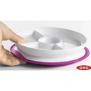 Divided plate by Oxo, featuring a pink non-slip base and multiple sections, being held by a hand.