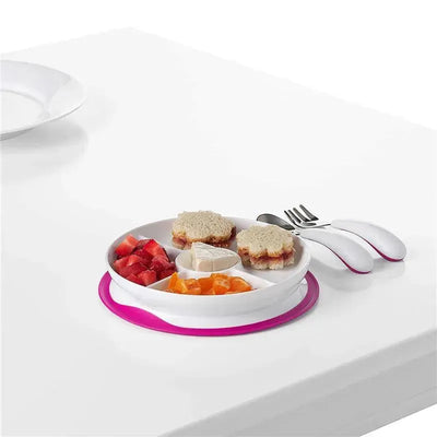 Divided pink plate with sections containing fruit, sandwich shapes, and a dip, accompanied by a pair of utensils.