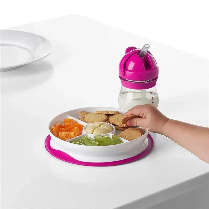 Oxo Tot Stick & Stay Divided Plate in pink with food sections; a child’s hand reaches for a cookie.