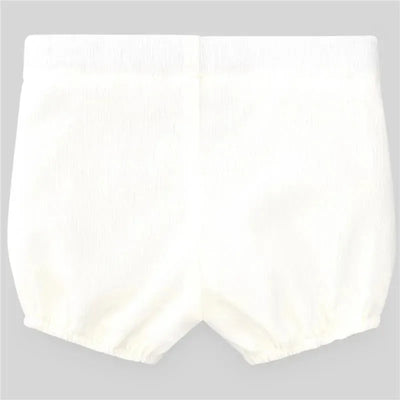 Cream-colored woven newborn shorts with elastic waistband, soft texture, and gathered leg openings.