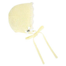 Knit newborn bonnet in soft yellow with lace trim, decorative bow, and ties for securing.