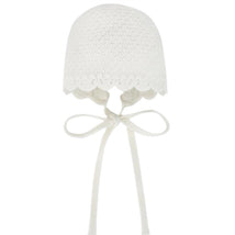 Knit newborn bonnet in chalk pink with scalloped edges and ribbon ties. Designed for babies.