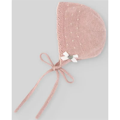 Powder pink and beige knitted newborn bonnet with a white ribbon and button detail, designed for infants.
