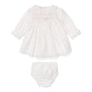 Light pink newborn dress with long sleeves, smocked detail, and matching bloomers. Perfect for infants.