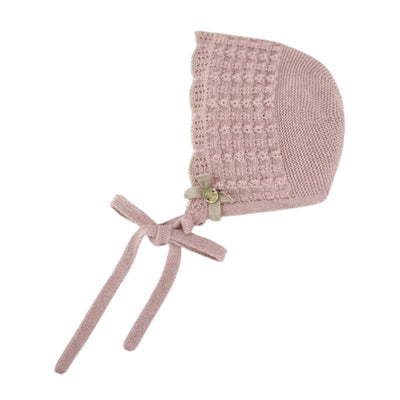 Knit newborn bonnet in powder pink and light brown, featuring a textured design, floral embellishment, and tie straps.