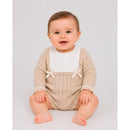 Newborn sitting and smiling, wearing a light brown and cream knit romper with a white collar and lace details.