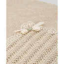 Light brown knit newborn shawl by Paz Rodriguez, featuring a floral lace trim and a decorative bow with a button.