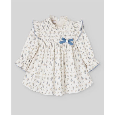 Woven newborn dress in cream with floral print, ruffled neckline, and blue bow detail. Perfect for infants.