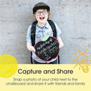 Child holding a chalkboard sign for their first day of kindergarten, stating their age and date, smiling joyfully.