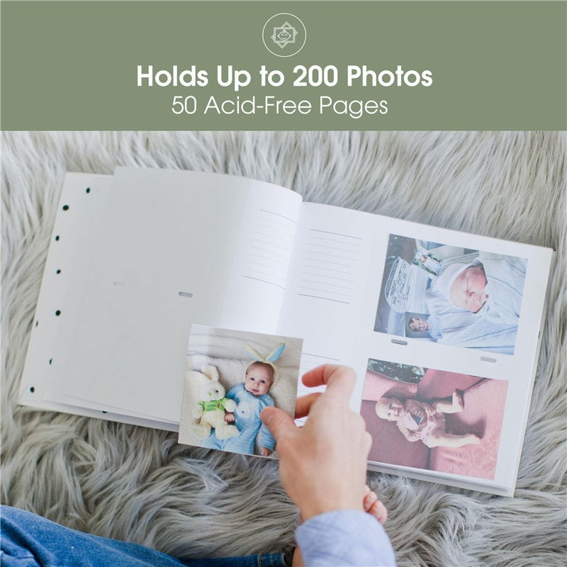 White polka dot baby photo album open to show guided journal pages, with a person holding a photo of a baby.