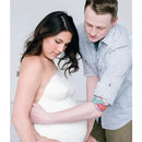 A pregnant woman and her partner are applying plaster to create a belly cast using the Pearhead Belly Casting Kit.