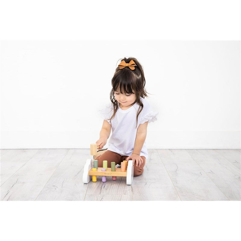 A young child plays with the Pearhead Montessori Hammer Bench Toy, using a wooden hammer to tap colorful pegs into a bench.