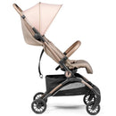 Peg Volo Compact Stroller in Mon Amour (Rose Gold) with a pink canopy and a beige seat, featuring a storage basket underneath.