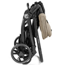 Folding PEG YPSI stroller from the Primo Viaggio Nido Travel System, featuring a sleek black frame and beige handle.
