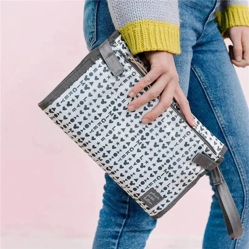 Diaper clutch featuring a playful pattern of hearts and Mickey Mouse icons, held by a person in jeans.