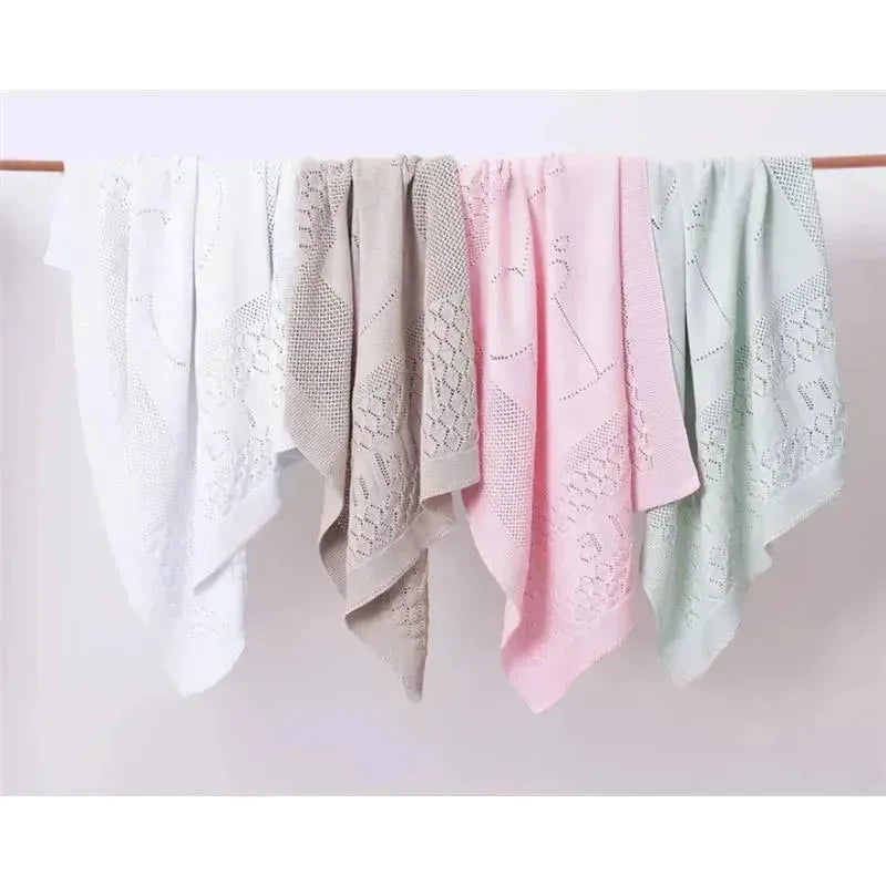 Pointelle design stroller blankets in white, beige, pink, and green, neatly arranged on a display.