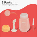 Pigeon baby weaning spoon, squeeze bottle with scale markings, and included cleaning brush on a red background.