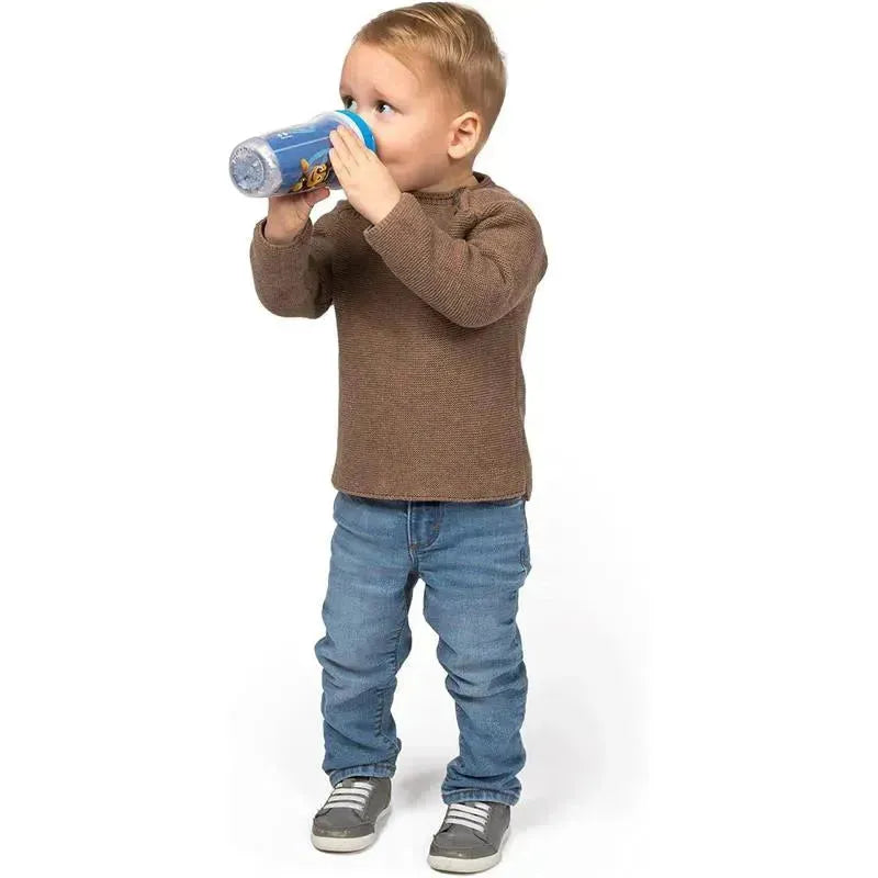 Toddler is drinking from a blue Paw Patrol glitter spout cup, wearing a brown sweater and jeans.