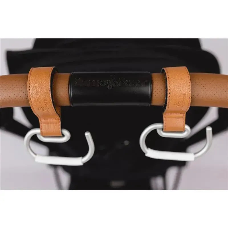Leather stroller hooks attached to a beige stroller handle, featuring a black Primo Passi logo.