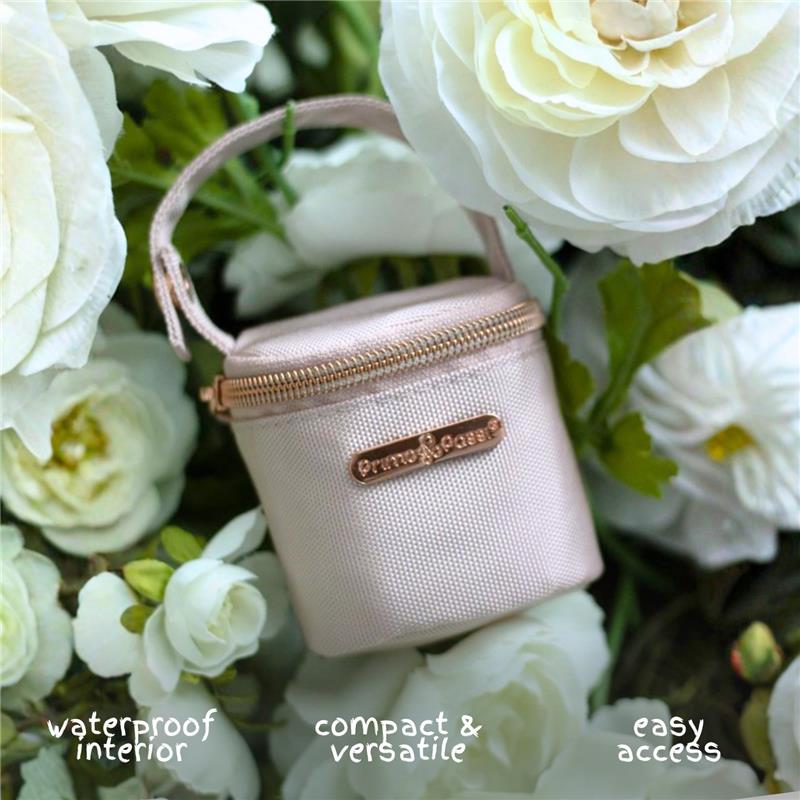 Pink Primo Passi pacifier bag with waterproof interior, surrounded by white flowers, featuring easy access and compact design.