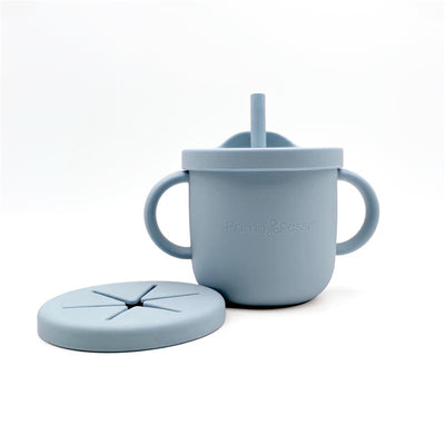 Silicone training cup and snack cup in dusty blue, featuring two handles and a removable lid with slits for easy access.