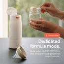 Portable milk warmer with a hand holding a measuring scoop over a glass jar, showcasing its formula preparation feature.