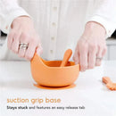 Silicone baby feeding set featuring an orange bowl with a suction grip base and a matching spoon.