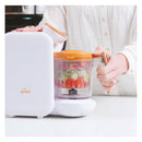 Quark Quook 5-In-1 Baby Food Processor with vegetables inside and a person operating the lid.