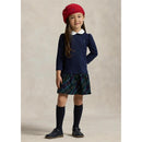 Girl wearing a navy long-sleeve collared shirt dress with a plaid skirt, casual shoes, knee-high socks, and a red beret.