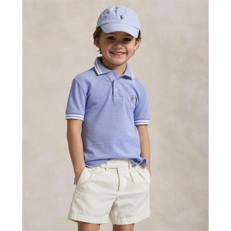 Short-sleeve cotton polo shirt in solid harbor island blue worn by a smiling child, paired with light-colored shorts and a matching cap.