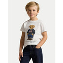 White short-sleeve t-shirt featuring a graphic of a bear in a sweater with an American flag, worn by a smiling child.