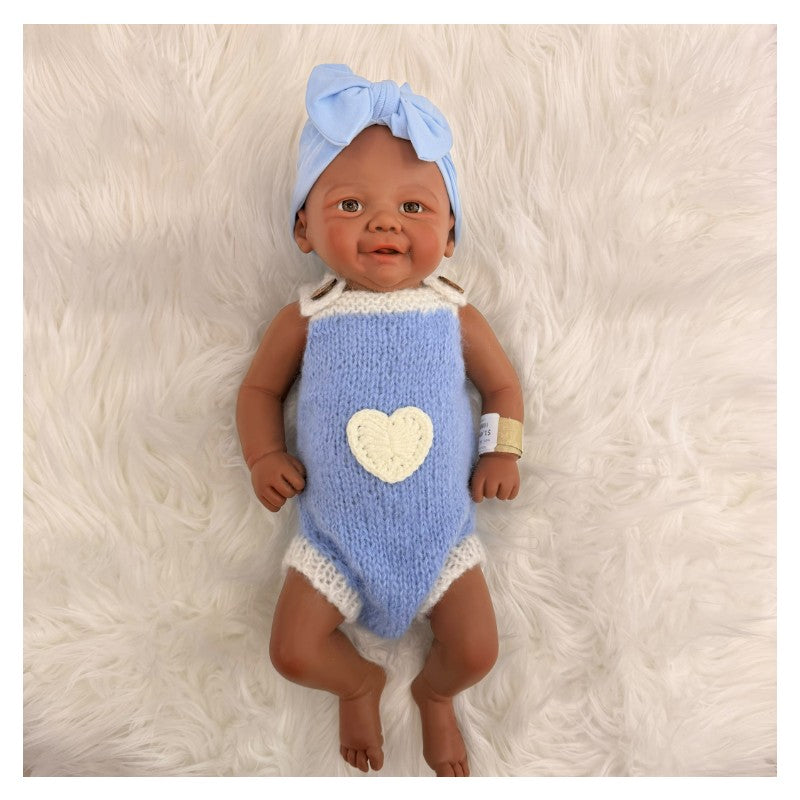 Reborn baby doll, African American, bald, wearing a blue outfit with a heart and a matching bow headband.