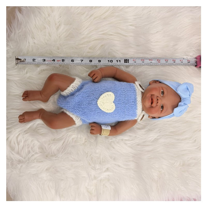 Reborn baby doll, African American vinyl, bald, wearing a blue outfit with a heart and a matching bow headband.