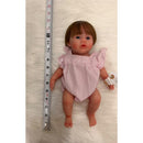 Full silicone reborn baby doll named Charlie, wearing a pink striped outfit, next to a measuring tape.