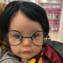 Reborn baby doll resembling Harry Potter, with black round glasses, blue eyes, and a red and yellow scarf.