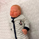 Reborn Baby Doll Leolonni with white vinyl skin, dressed in a striped onesie featuring an anchor motif.