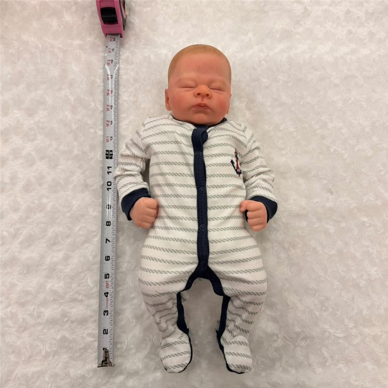 Reborn baby doll in a white and navy striped onesie, measuring 22 inches, with realistic features and closed eyes.
