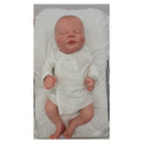 Reborn Doll White Vinyl Ever dressed in a white outfit, lying on a padded surface with a serene expression.