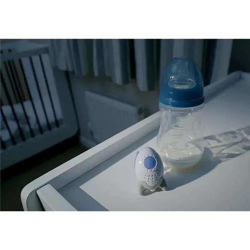 Portable sound-soother Rockit beside a baby bottle on a bedside table in a softly lit nursery.
