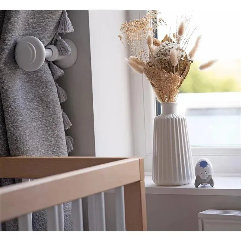 Rockit portable sound-soother on a windowsill next to a decorative vase and curtains in a nursery setting.