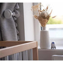 Rockit portable sound-soother on a windowsill next to a decorative vase and curtains in a nursery setting.