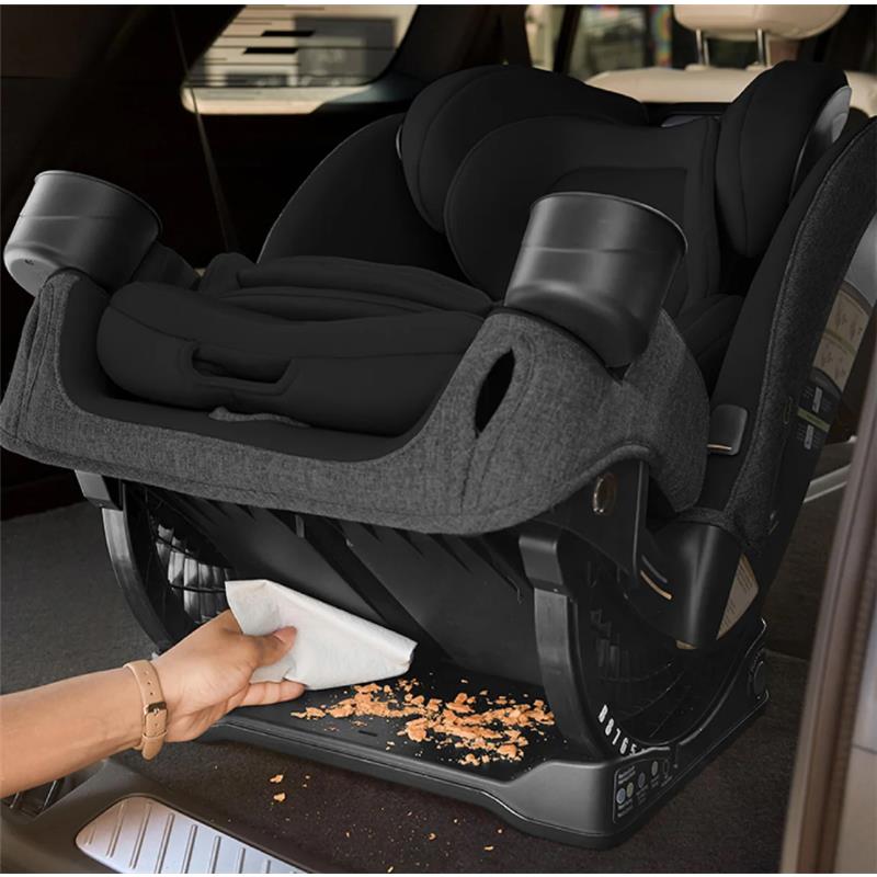Romer Nexa All-in-One Convertible Car Seat in Peppercorn, being cleaned with a cloth, showing crumbs on the floor underneath.