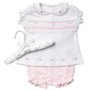 Short-sleeve white top with pink floral embroidery paired with pink ruffled shorts, displayed on a hanger.